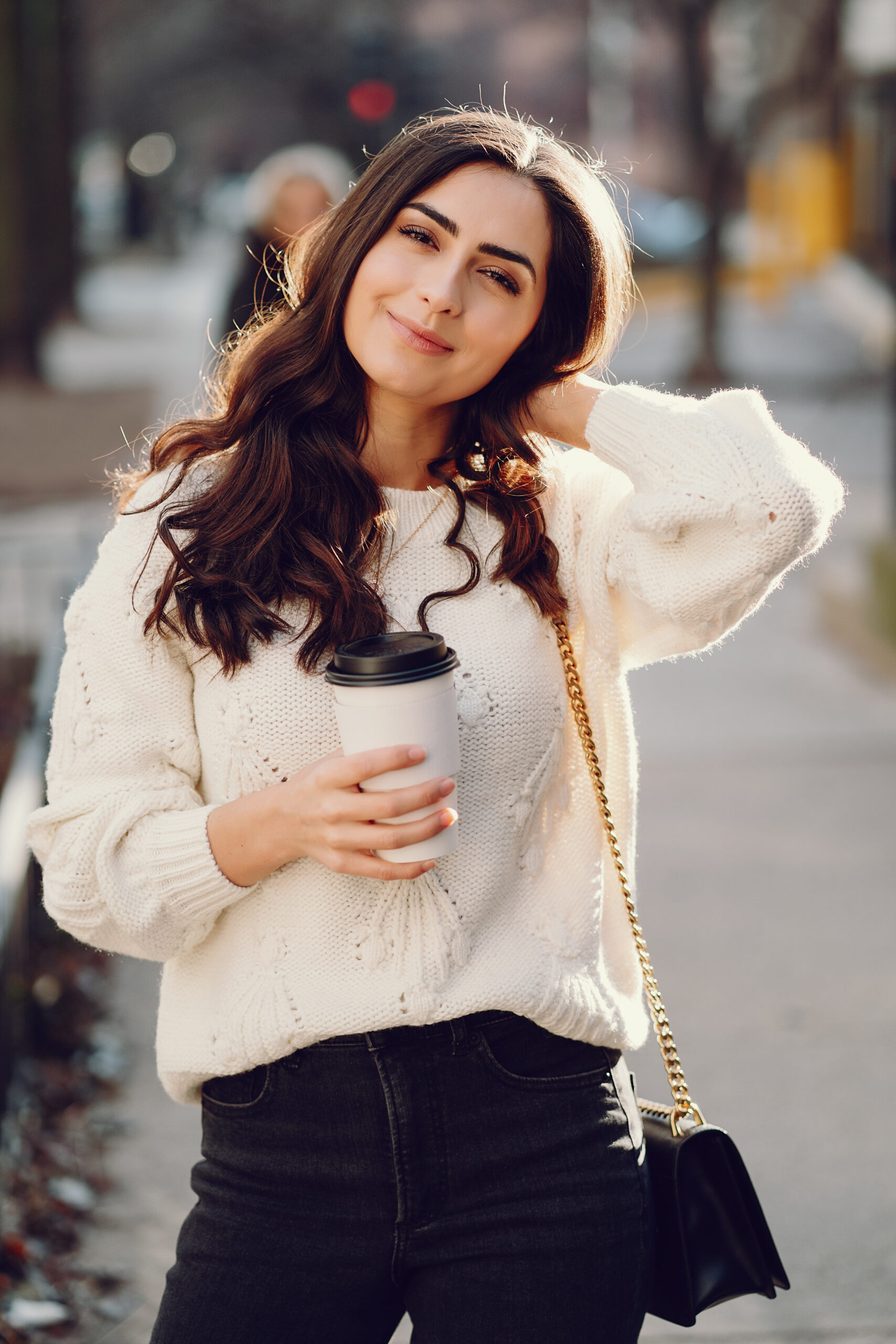 cute brunette in a white sweater in a city